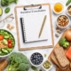 Elegant flat lay of nutritious foods and a nutrition consultation notebook on a marble surface, symbolising personalised nutrition support.