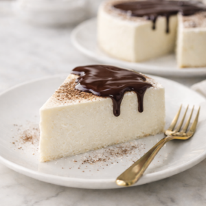 High-protein keto no-bake New York cheesecake topped with melted dark chocolate on a white plate