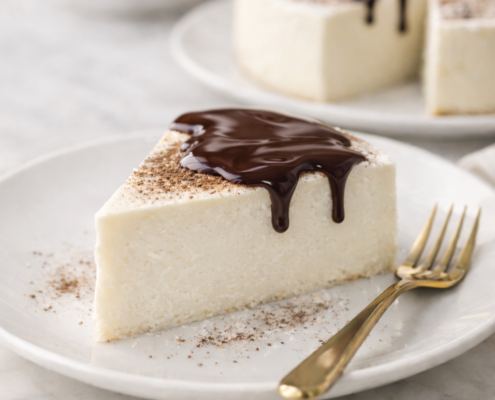 High-protein keto no-bake New York cheesecake topped with melted dark chocolate on a white plate